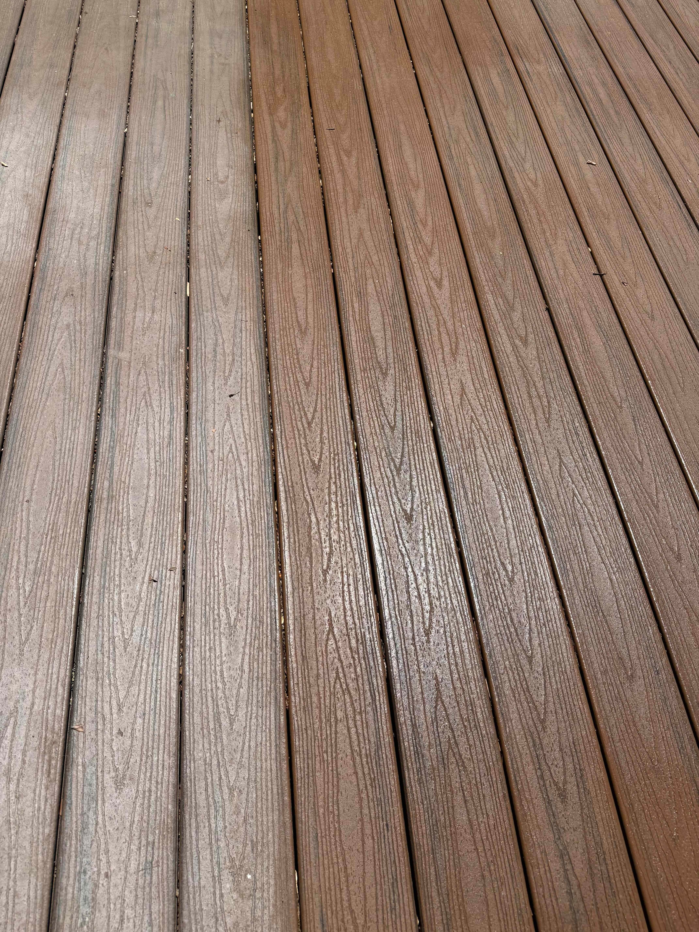 Close-up of composite deck restoration showing color difference between treated and untreated boards